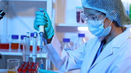 Scientists are doing research in a science lab. A medical chemist in a white coat, gloves and goggles looks at a glass tube. Compare two different liquid samples. and discuss future experiments.