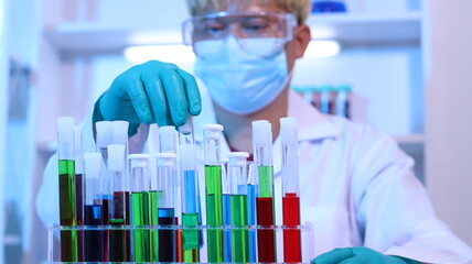 Scientists are doing research in a science lab. A medical chemist in a white coat, gloves and...