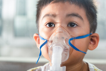 Asian Child using nebulizer mask equipment alone have smoke, Kid boy making makes inhalation nebulizer steam sick cough at home, oxygen spray inhaler therapy, stuffy nose and runny, Health medical - obrazy, fototapety, plakaty