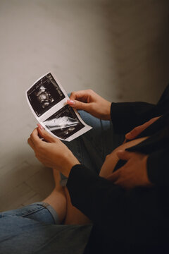Close up photo of pregnant woman and her husband looking at the ultrasound picture. Family concept