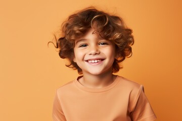 Portrait of smiling little girl with curly hair on orange background.