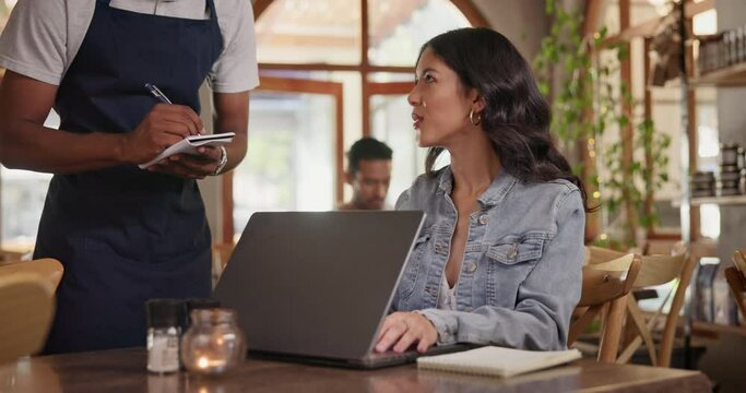 Cafe, waitress and freelancer customer with laptop, typing feedback for restaurant review blog on social media. Coffee shop, order and woman with remote work and server writing menu info on notebook