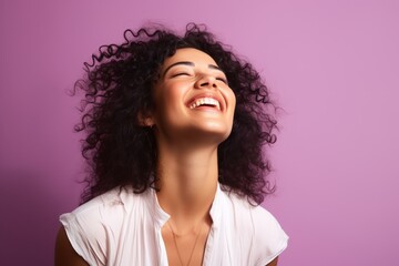 Portrait of a happy young african american woman laughing and looking up on purple background