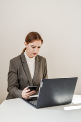 a beautiful woman in a gray suit works at a laptop