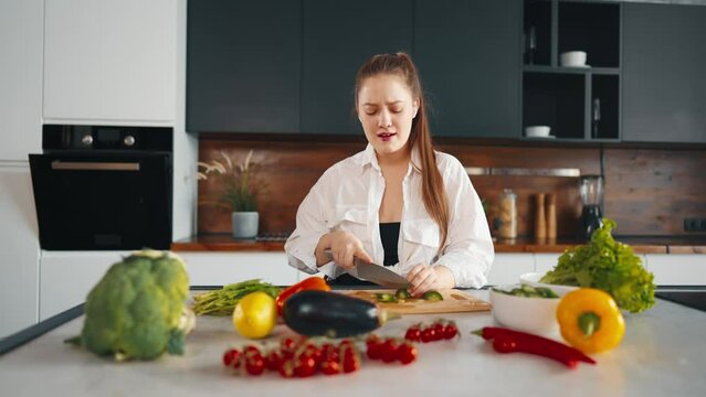 Young woman cooking, dancing at kitchen. Girl cook healthy food listen to music with headphones and dancing in kitchen. Girl with vegetables play radio and dance, while cooking salad have fun at home.