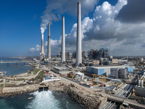 Big coal power station with tall chimnies and coal conductor and white steam - aerial shot in  Hadera