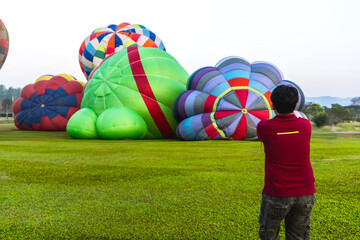 Back view man looking at hot air fire balloons on ground