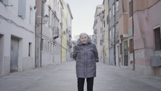 Elderly lady standing between ancient buildings