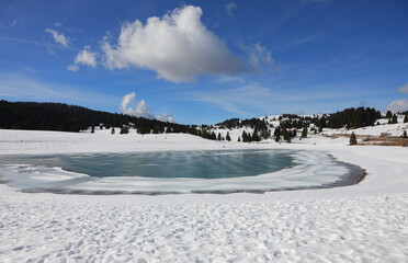 breathtaking view with artifical frozen lake in winter with snow and white clouds - obrazy, fototapety, plakaty