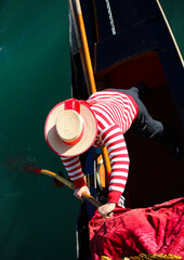 gondolier with hat rowing on gondola boat on grand canal in Venice in Italy