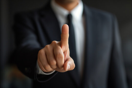 A businessman is pointing at something invisible, with the focus on his finger, likely indicating a touchscreen or virtual screen in line with a technology or business concept.