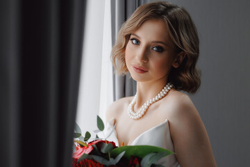 Portrait of happy elegant young woman in modern bridal look with classic hairstyle and makeup hold...