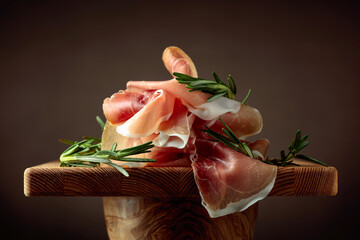 Prosciutto with rosemary on a brown background.