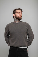 Cool fashion studio male portrait, handsome hipster man with hairstyle and beard with glasses in a fashionable knitted sweater on a white background