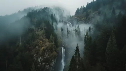 Foto op Aluminium Aeriel view of waterfall between trees of high hills in a foggy day. Water flows down to rocky mountain. © Emil