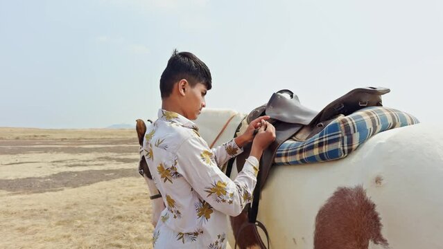 man preparing to ride a piebald horse in an open field with a focus on companionship and adventure