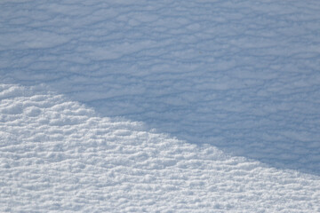 Diagonal shadow on textured white snow abstract winter background