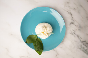 Burrata and basil on a plate, mozzarella cheese specialty, aromatic basil leaf, Italian delight
