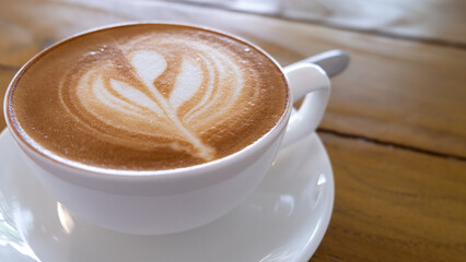 Close up of delicious flat white coffee with tulip latte art in a clean and simple white cup and saucer on a rustic vintage wooden table at local coffee shop