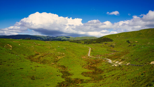 country road along the hillside, beautiful blue summer sky with clouds, Palmerston North, New Zealand