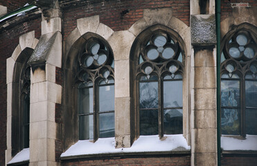 Three old pointed gothic windows with stained glass on facade of the building. Baroque and Gothic architecture. Church of St. Olga and Elizabeth. Lviv, Ukraine.