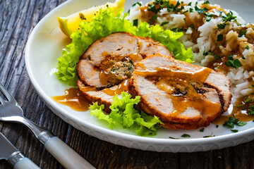 Stuffed turkey breast roulade with dried apricots and cranberries and boiled white rice on wooden...