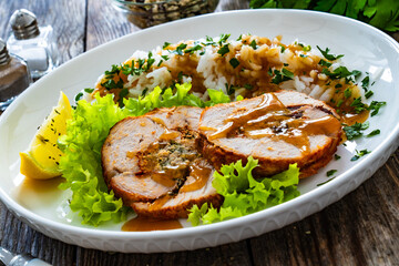 Stuffed turkey breast roulade with dried apricots and cranberries and boiled white rice on wooden table
