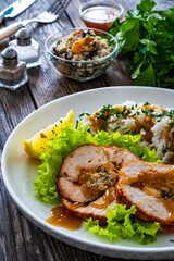 Stuffed turkey breast roulade with dried apricots and cranberries and boiled white rice on wooden table
