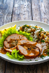 Stuffed turkey breast roulade with dried apricots and cranberries and boiled white rice on wooden table
