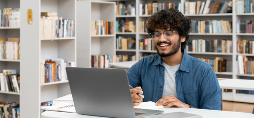 Banner smiling indian male student studying online watch webinar using laptop computer, having...