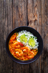 Fried shrimps with rice in mango sauce on wooden table
