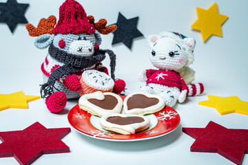 Various homemade cookies from the Christmas bakery on a small plate. And a moose and a cat amigurumi figures with Christmas clothes.