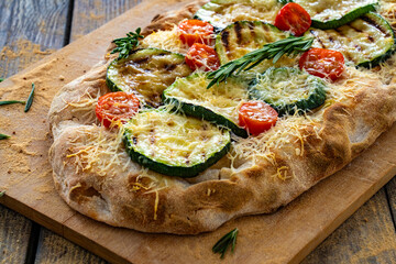 Pinsa Romana with mozzarella cheese and grilled zucchini and rosemary on wooden table