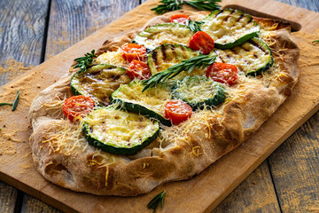 Pinsa Romana with mozzarella cheese and grilled zucchini and rosemary on wooden table