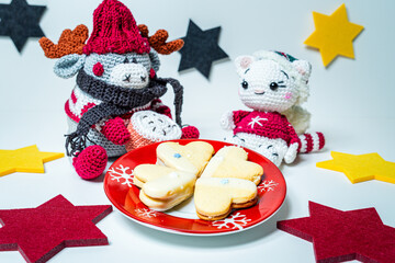 Various homemade cookies from the Christmas bakery on a small plate. And a moose and a cat amigurumi figures with Christmas clothes.