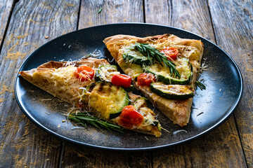 Pinsa Romana with mozzarella cheese and grilled zucchini and rosemary on wooden table