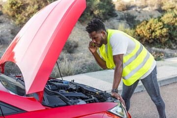 Man in Yellow Vest Looking Under Hood of Red Car