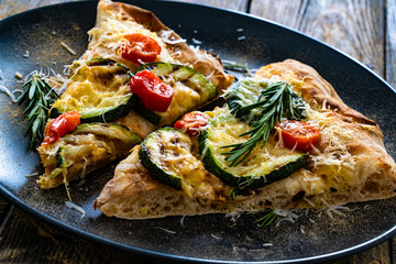 Pinsa Romana with mozzarella cheese and grilled zucchini and rosemary on wooden table