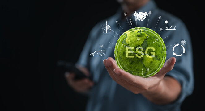 Businessman holds globe with ESG icons, symbolizing commitment to environmental, social governance. Represents green business and sustainable world practices