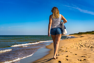 Beautiful mid adult woman walking on sunny beach
