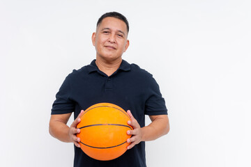 Portrait of a confident middle-aged Asian man holding a basketball with a friendly smile, isolated on a white background.