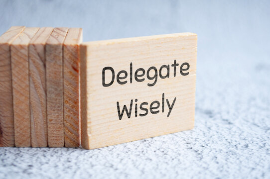 Delegate wisely text on wooden blocks. Delegation of duty concept