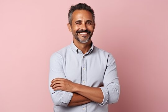 Portrait of a handsome middle-aged man with crossed arms against pink background