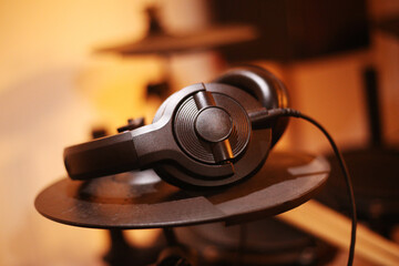 close-up of wired headphones on black drum cymbal. Music online enjoy listening. Concept drum...