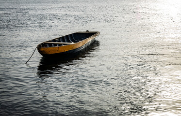 Small wooden boat anchored in the lake. Fisherman's boat.
