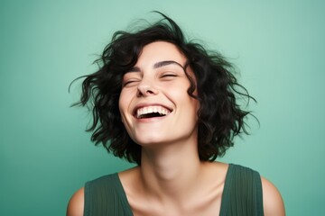 Portrait of a happy young woman laughing with closed eyes over green background - obrazy, fototapety, plakaty