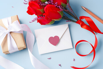 White envelope with heart, kraft gift box and rose on blue background