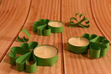 Four-leaf clover and candles on peatch background. St. Patrick's Day