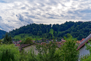 Fototapeta na wymiar Scenic landscape with traditional houses at Slovenian City of Skofja Loka on a cloudy summer day. Photo taken August 9th, 2023, Škofja Loka, Slovenia.
