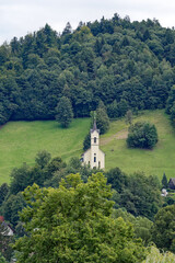 Holy Cross Church at Pustal settlement on a hill at municipality of Slovenian City of Skofja Loka on a cloudy summer day. Photo taken August 9th, 2023, Škofja Loka, Slovenia. - obrazy, fototapety, plakaty